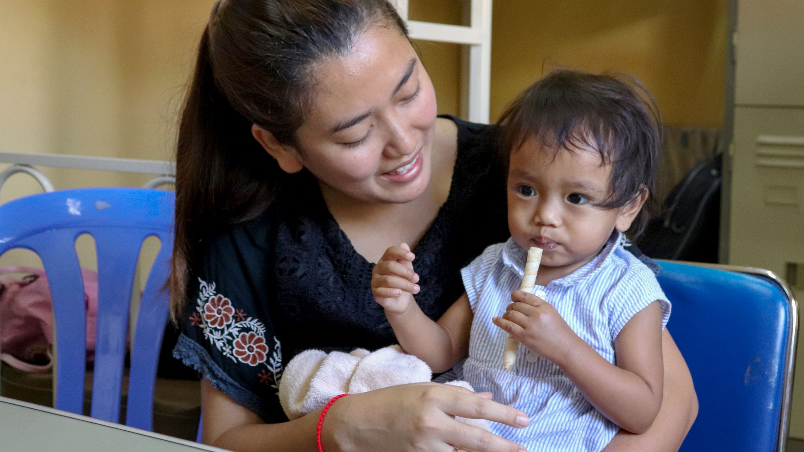 A woman holds her child on her lap, Cambodia