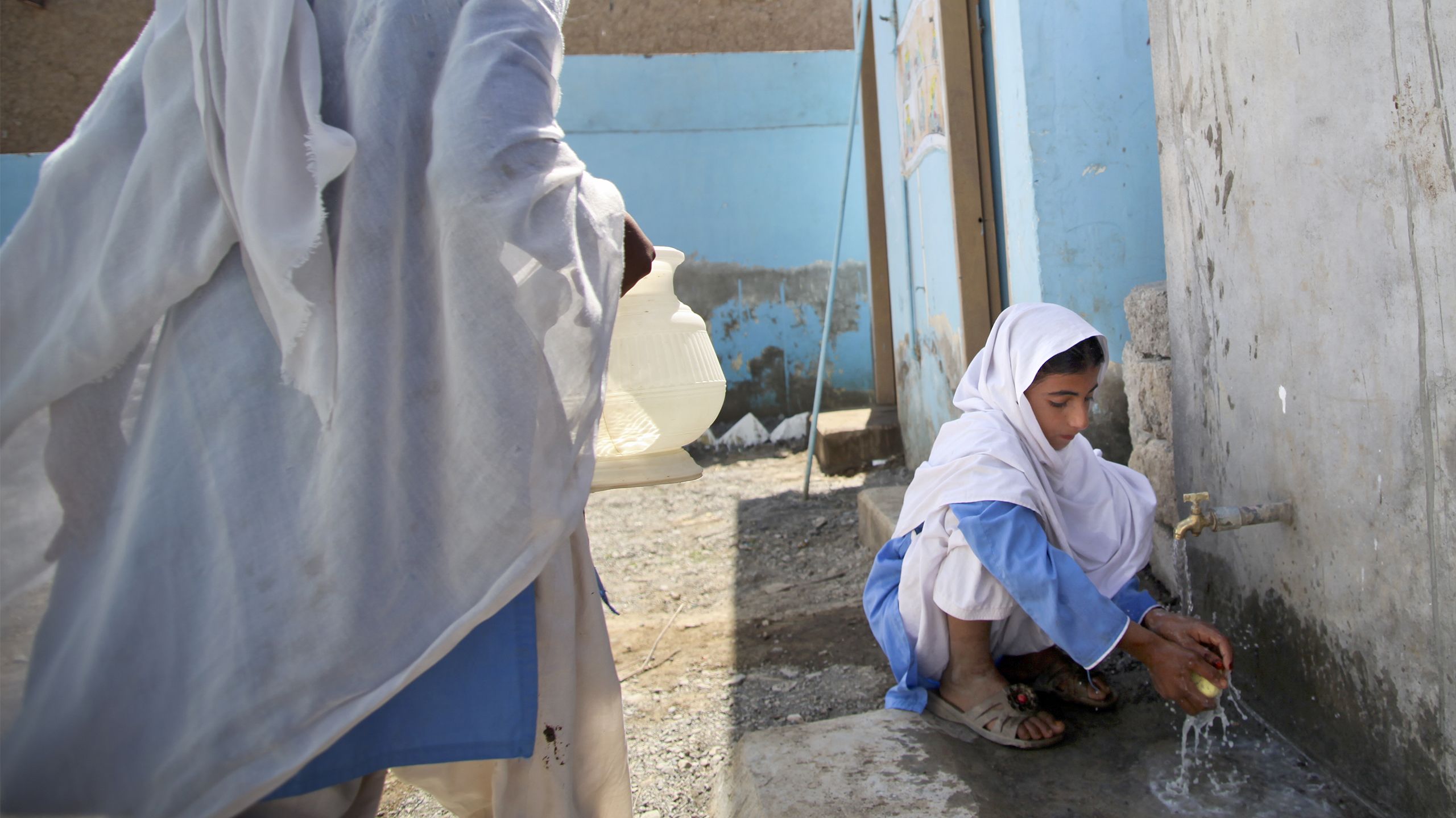 A girl washes her hands with water from a tap, Pakistan