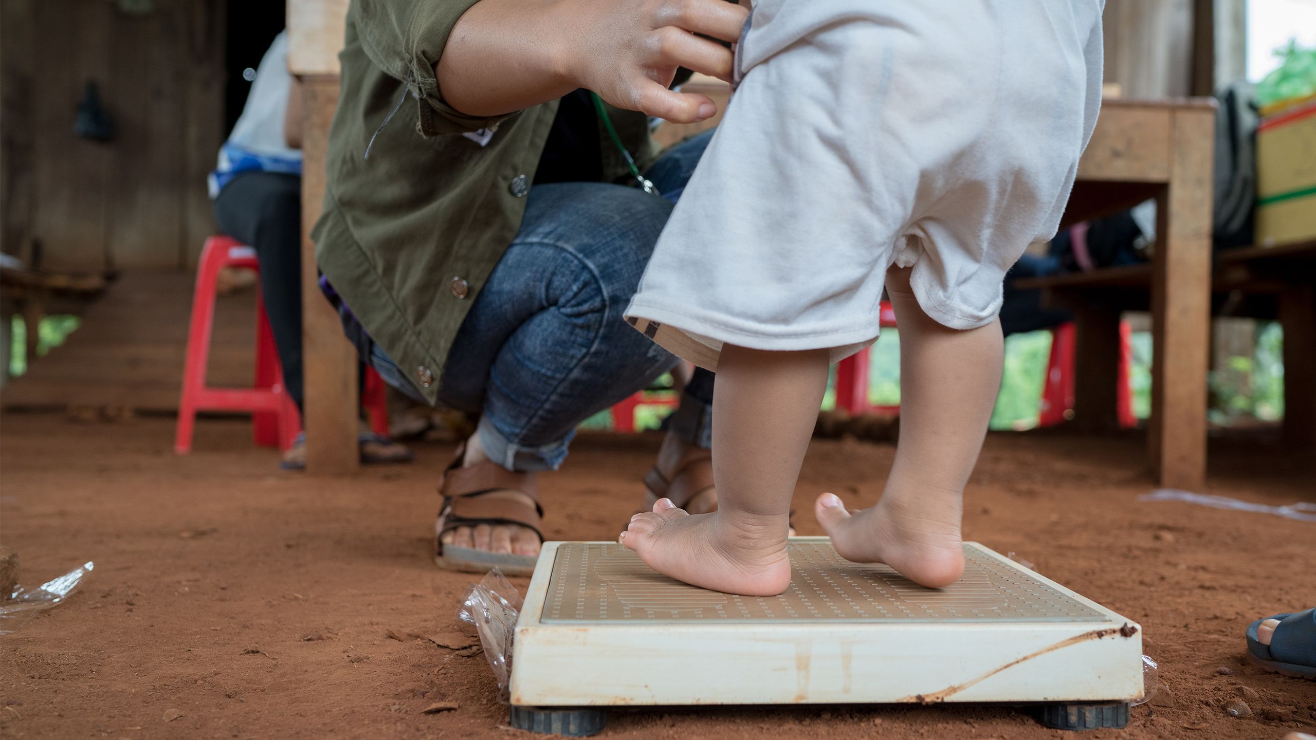 Un enfant se tient debout sur un pèse-personne, Cambodge 
