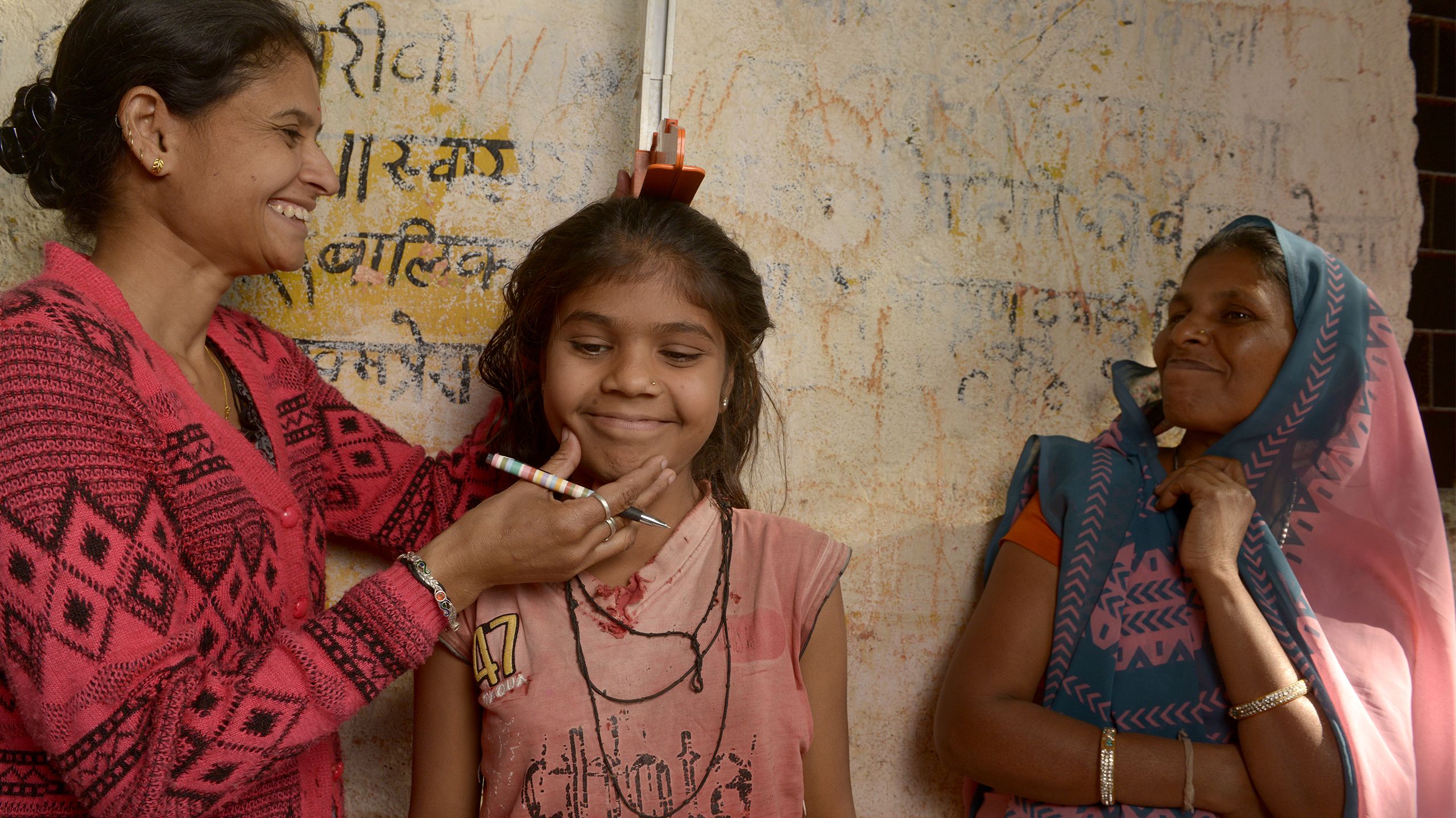 Une femme mesure la taille d'une fille, Inde